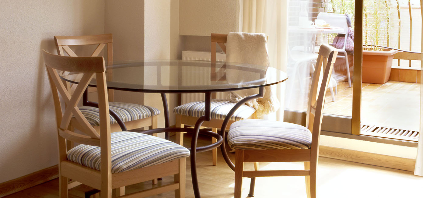 Comedor con mesa redonda de cristal, sillas de madera tapizada y preciosa terraza
