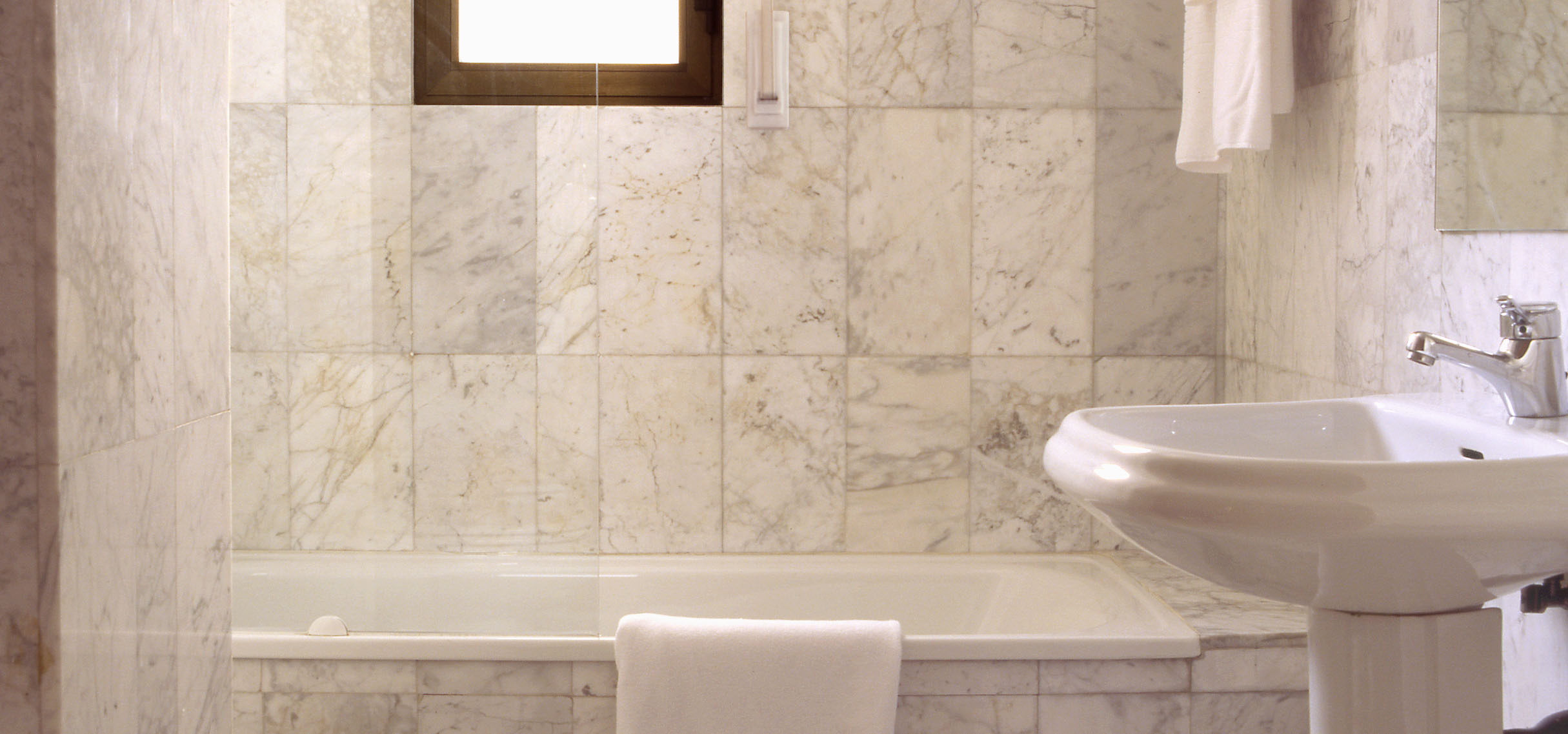 Elegante y distinguido servicio con bañera, suelos y paredes revestidas en mármol y con luz natural
